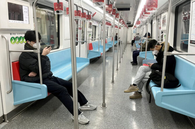 FILE PHOTO: Commuters wear protective masks while they ride a subway train as COVID-19 outbreaks continue in Shanghai