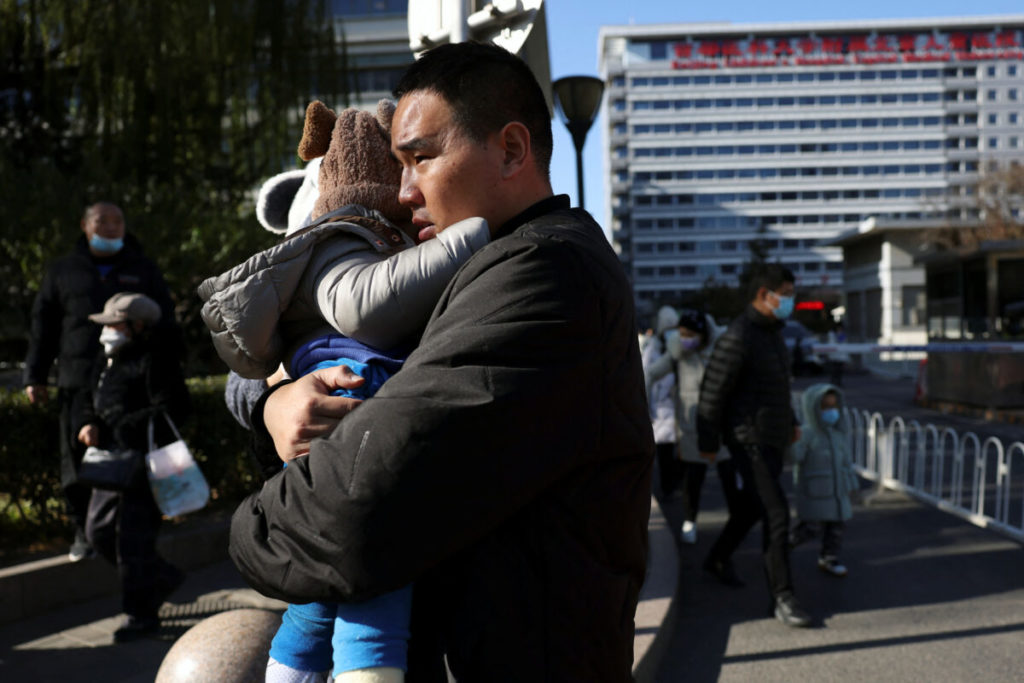 Man carries a child outside a children's hospital in Beijing