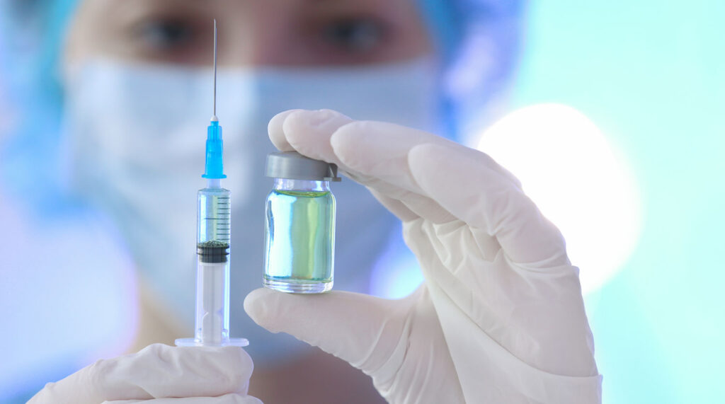 Doctor holding syringe and medicine for vaccination, closeup